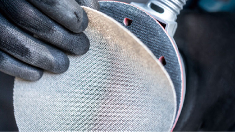 兩隻戴著黑手套的手握著一個磨盤。