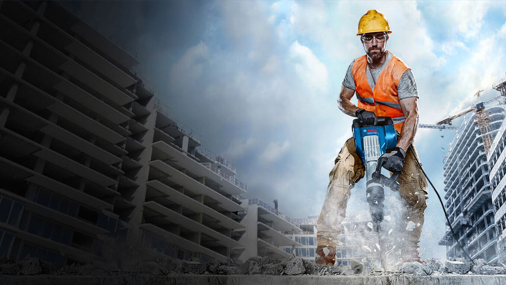 一個戴著安全帽和橙色背心的男人正在使用博世錘。