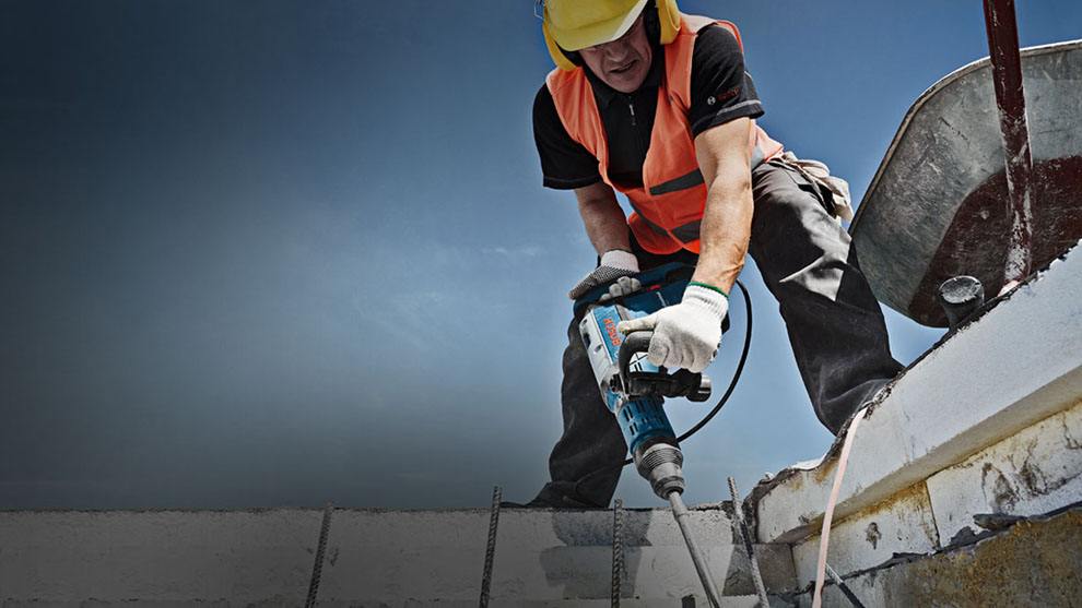 穿著警示背心的工人在工地上使用博世電鑽。