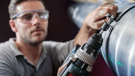 一名戴著護目鏡的工匠正在使用一台黑色博世電鑽。