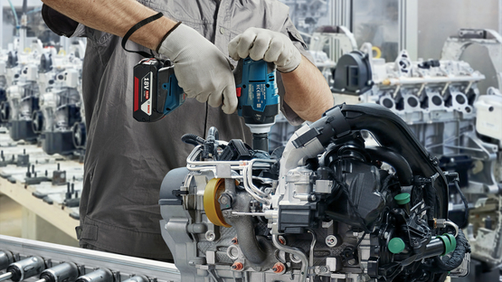 一名戴著安全帽和口罩的工人正在使用博世專業工具。