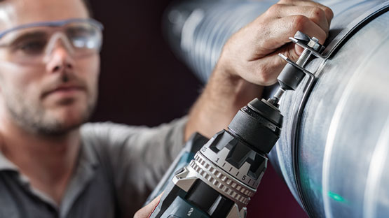 一名工匠在一根管道上使用博世專業電鑽。