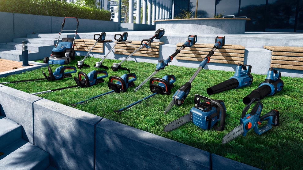 一系列藍色園藝工具放在綠色草坪上，包括割草機、修剪機和吸葉器。