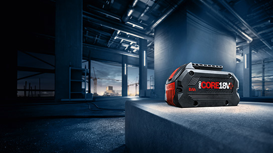 一個黑色的博世專業電池放在建築工地的灰色混凝土塊上。