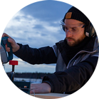 一個戴著耳機的男人在戶外用博世鋸切割木材。