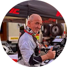 一個戴著頭盔和賽車服的男人在帳篷和工具前豎起大拇指。