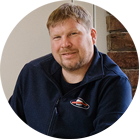 一個微笑的短髮男人穿著藍色毛衣。