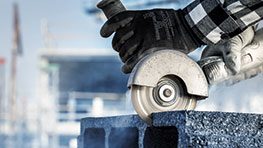 一隻戴著手套的手握著一個角磨機，正在處理混凝土。