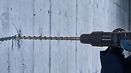 博世專業鑽頭穿透一面灰色混凝土牆。