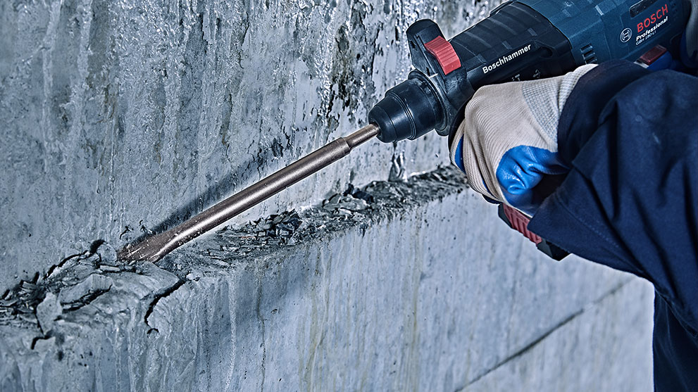 一隻手在牆上操作博世專業鑽孔機。
