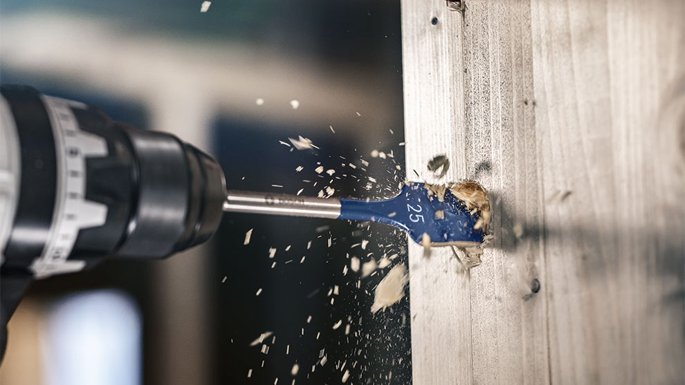 博世專業電鑽在木板上鑽孔，木屑飛舞。