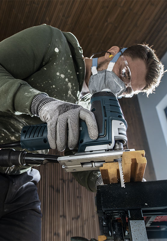 一個戴著護目鏡和口罩的男人正在使用博世電鋸。