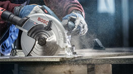 博世專業手持圓鋸正在切割木材，灰塵飛揚。
