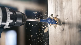 博世專業電鑽正在鑽一塊木頭，木屑飛舞。